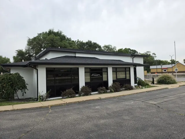 Single-story commercial building painted white with black trim and dark windows