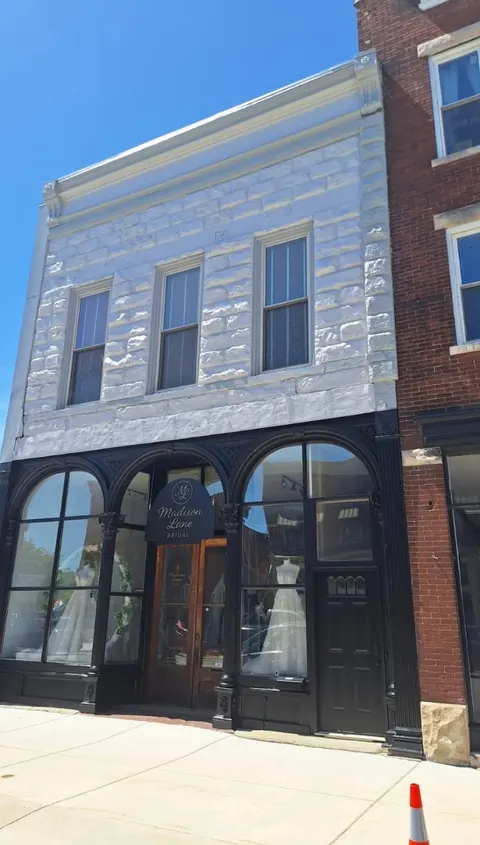 Historic two-story storefront with a painted white stone facade and black trim