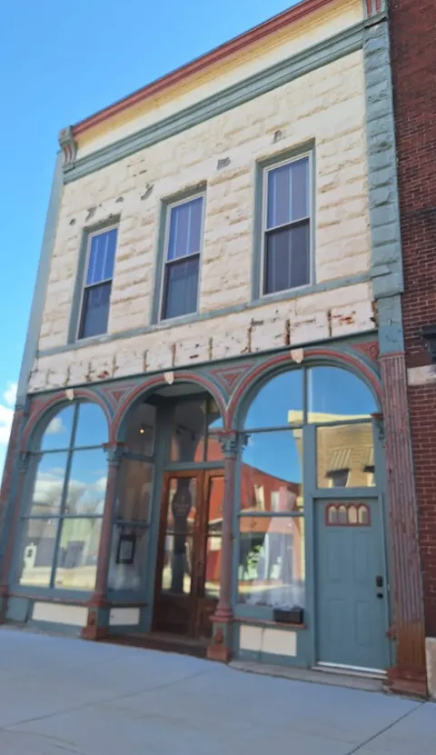 Historic two-story storefront with a cream stone facade and teal trim